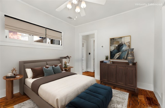 bedroom with visible vents, baseboards, wood finished floors, and ornamental molding