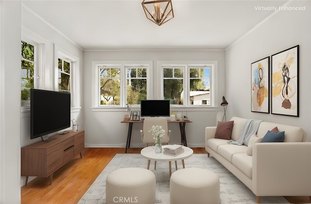 living area with baseboards, plenty of natural light, light wood-style flooring, and crown molding