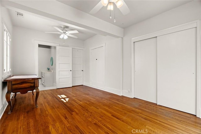 bedroom with ceiling fan, visible vents, and wood finished floors