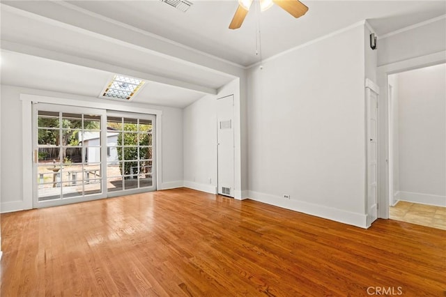 spare room featuring visible vents, crown molding, baseboards, and wood finished floors