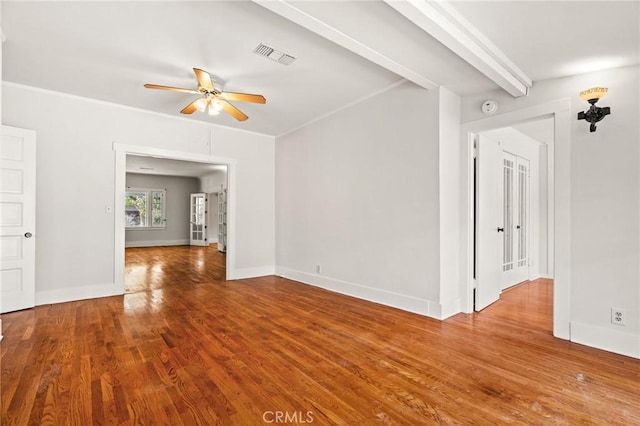 empty room with wood finished floors, baseboards, visible vents, beam ceiling, and ceiling fan