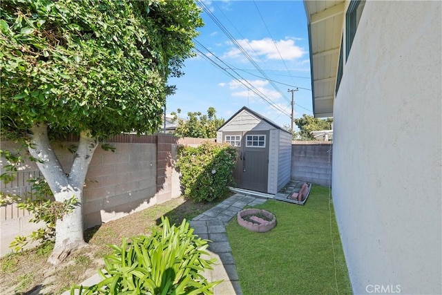 view of yard featuring an outbuilding, a fenced backyard, and a storage shed