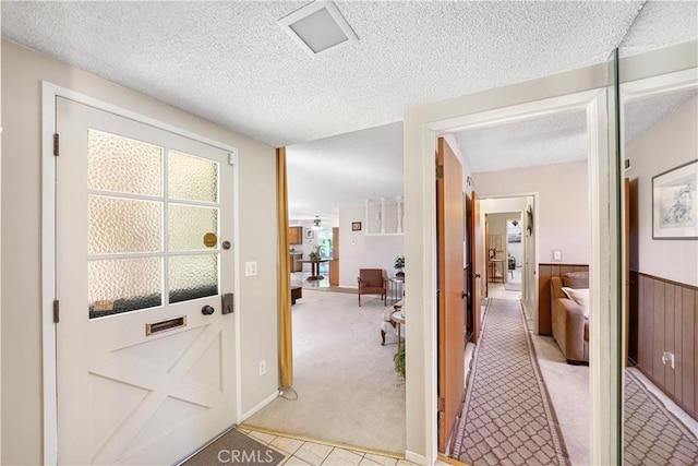 interior space featuring a textured ceiling, a wainscoted wall, light carpet, and wooden walls