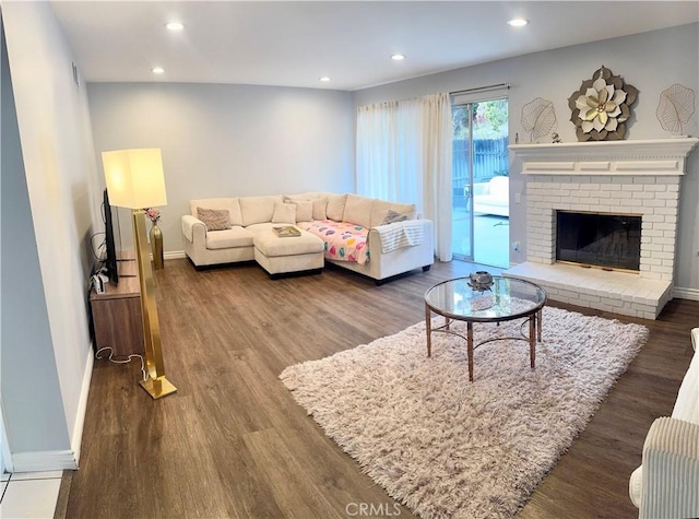 living area with a fireplace, recessed lighting, wood finished floors, and baseboards