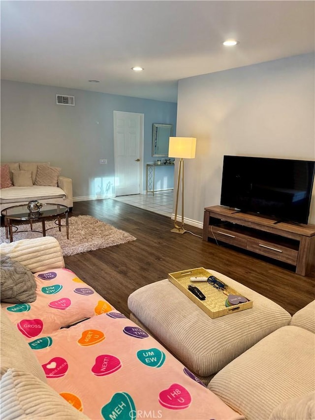 living room featuring visible vents, baseboards, wood finished floors, and recessed lighting