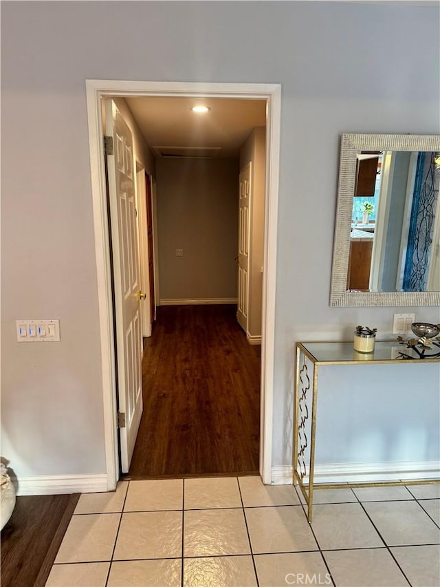 corridor featuring light tile patterned floors and baseboards