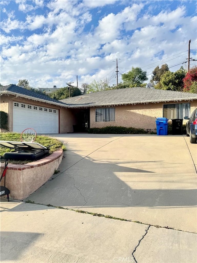 single story home with concrete driveway, an attached garage, and stucco siding