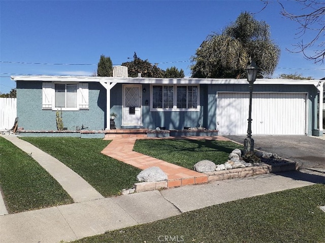 view of front of property featuring a front lawn, an attached garage, driveway, and a chimney