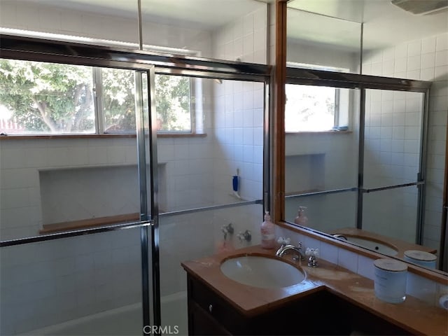 bathroom with a shower with door, visible vents, a healthy amount of sunlight, and vanity