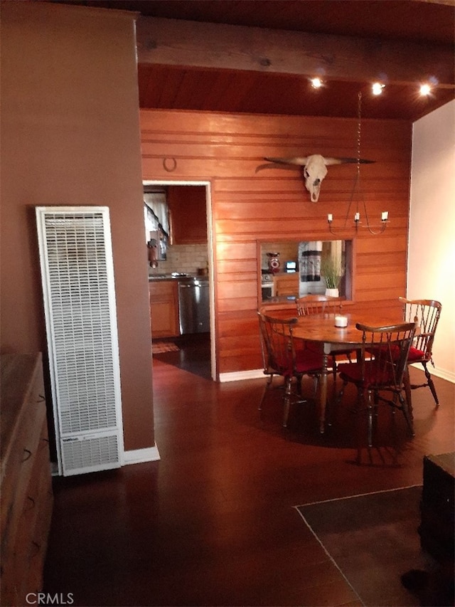 dining space with wood finished floors, wooden walls, beamed ceiling, and a heating unit