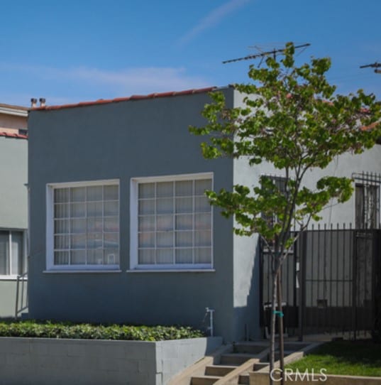 view of side of home featuring fence and stucco siding