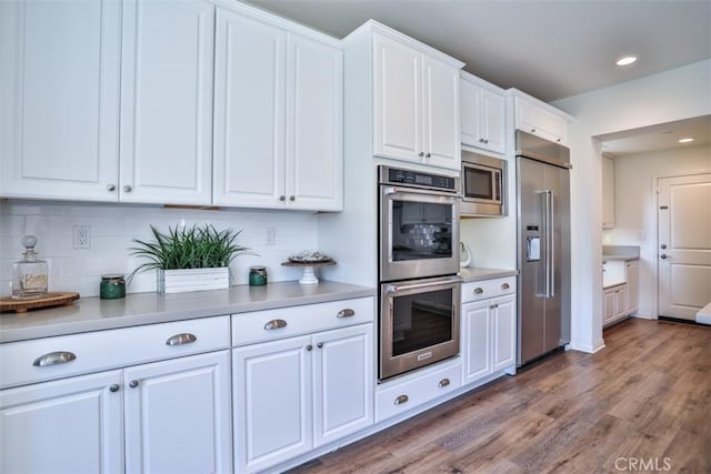 kitchen featuring light countertops, built in appliances, and white cabinets