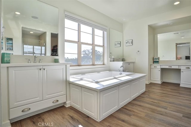 full bathroom featuring wood finished floors, vanity, and a bath