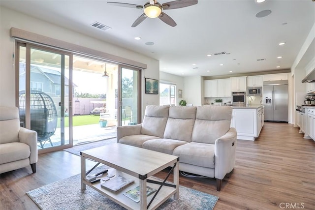 living room featuring a ceiling fan, visible vents, recessed lighting, and light wood-type flooring