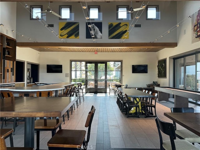 dining area with plenty of natural light, visible vents, a towering ceiling, and french doors