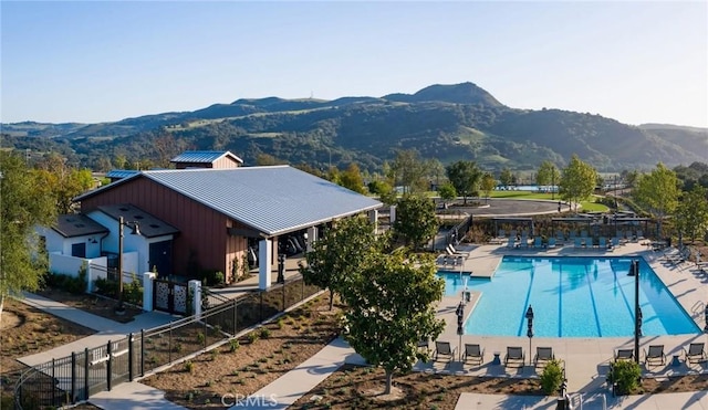 community pool featuring a mountain view, fence, and a patio area
