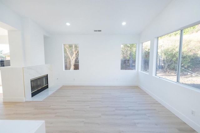 unfurnished living room featuring recessed lighting, a high end fireplace, visible vents, and light wood-style floors