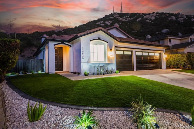 view of front of home with a tile roof, a yard, stucco siding, concrete driveway, and a garage