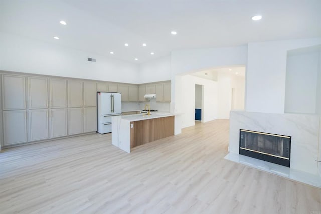 kitchen featuring under cabinet range hood, a high end fireplace, open floor plan, light countertops, and freestanding refrigerator