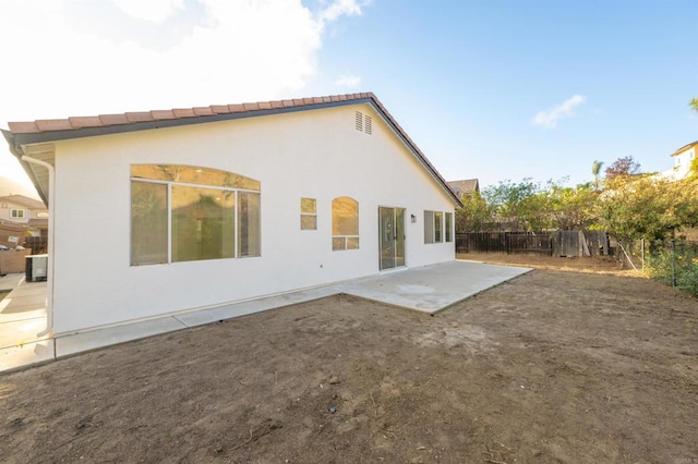 rear view of house with a patio, fence, and stucco siding