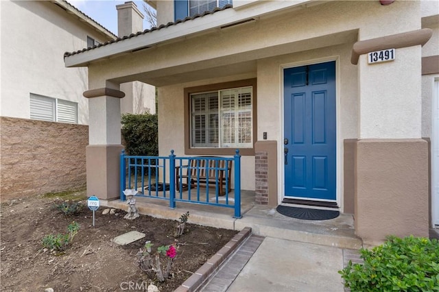 entrance to property with a porch and stucco siding