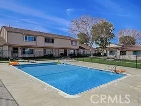 community pool with a patio area and fence