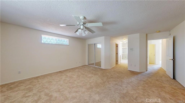 unfurnished bedroom with light carpet, ceiling fan, a textured ceiling, and a closet