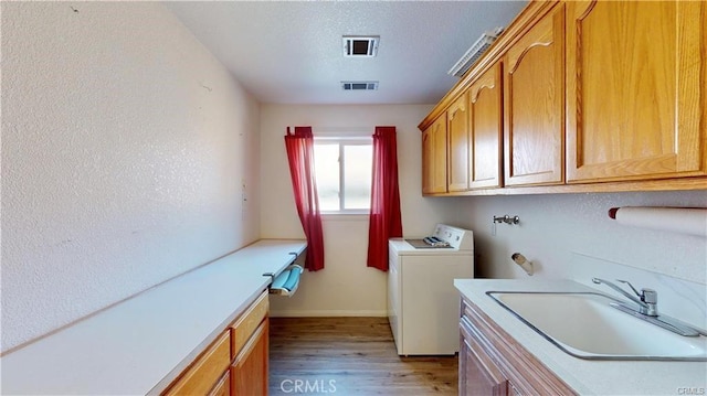 laundry room with washer / clothes dryer, cabinet space, visible vents, light wood-style flooring, and a sink