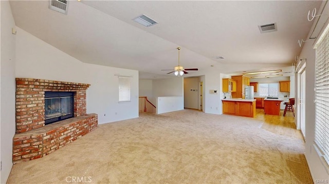 unfurnished living room with lofted ceiling, a fireplace, and visible vents