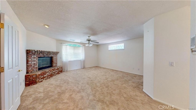 unfurnished living room featuring light carpet, ceiling fan, a textured ceiling, and a brick fireplace