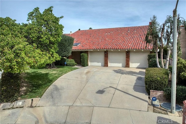 view of front facade with a garage, a tiled roof, and driveway