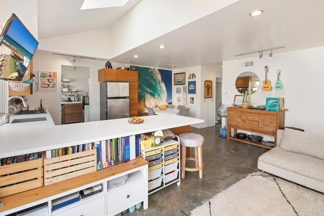 kitchen with recessed lighting, finished concrete floors, freestanding refrigerator, a sink, and vaulted ceiling with skylight