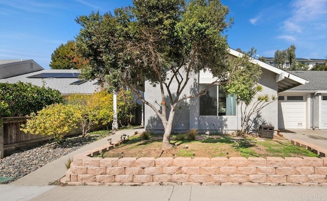 view of front facade featuring an attached garage, fence, and stucco siding