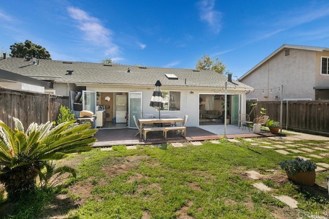 back of property with stucco siding, a fenced backyard, roof with shingles, and a yard