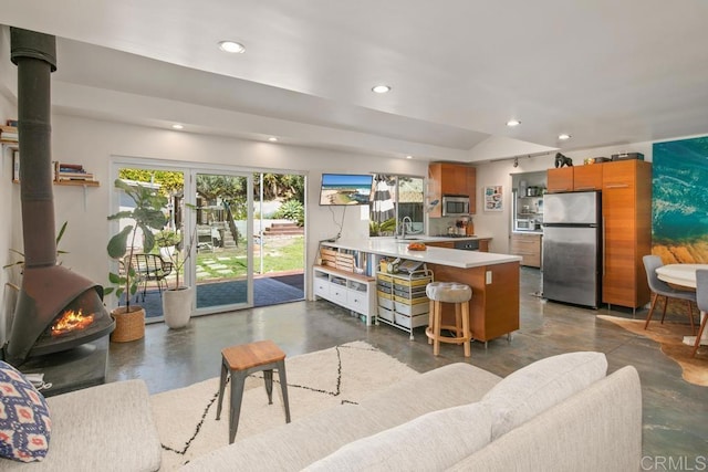 kitchen with stainless steel appliances, recessed lighting, a wood stove, and finished concrete floors