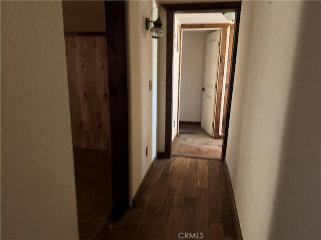 corridor with dark wood-style floors and baseboards