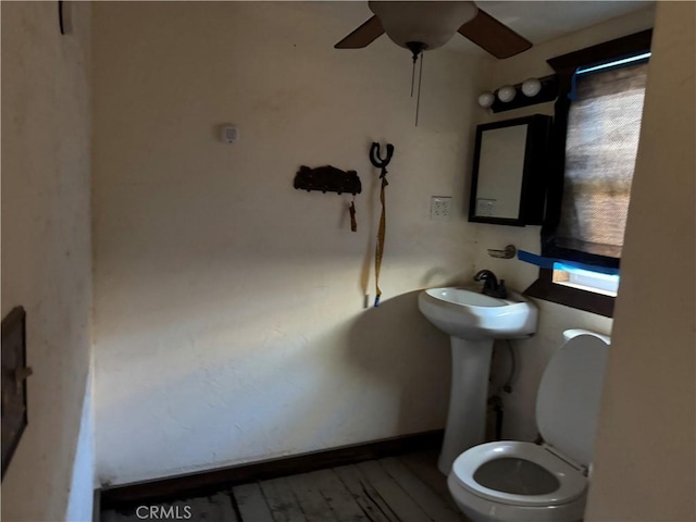 half bathroom with toilet, ceiling fan, baseboards, and wood finished floors