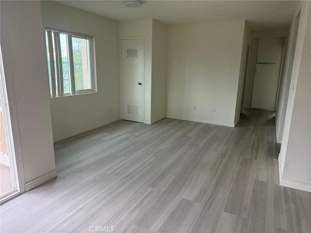 unfurnished bedroom with light wood-style flooring, visible vents, and baseboards