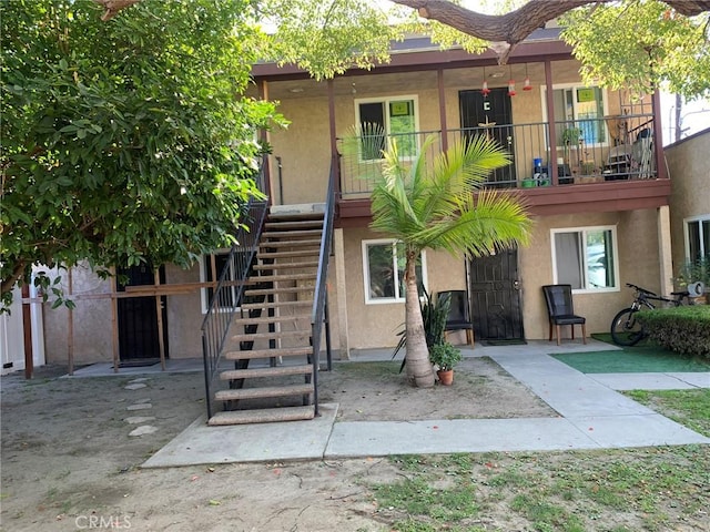 exterior space with stairs, a patio, and stucco siding