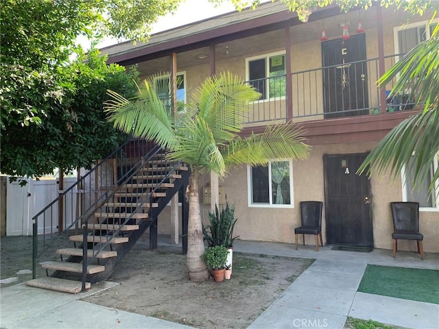 exterior space with stairs, a patio area, fence, and stucco siding