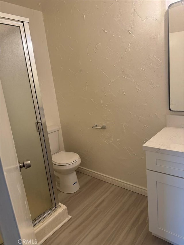 full bath with a textured wall, toilet, wood finished floors, vanity, and baseboards