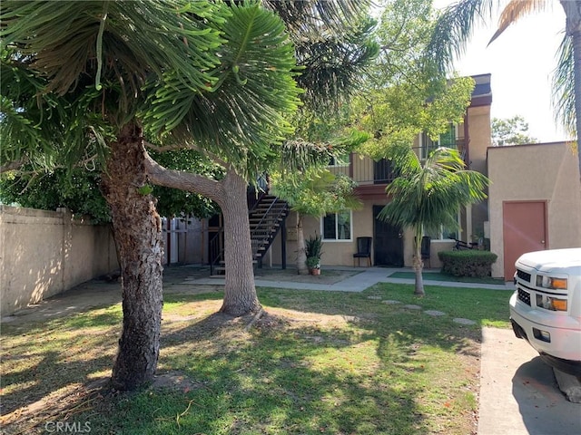 exterior space with stairs, a front lawn, fence, and stucco siding