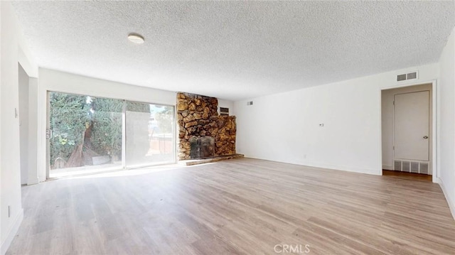 unfurnished living room featuring visible vents, a textured ceiling, and wood finished floors