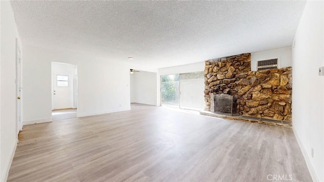 unfurnished living room featuring visible vents, a fireplace, a textured ceiling, and wood finished floors