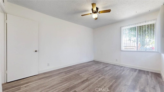 spare room with a ceiling fan, a textured ceiling, baseboards, and wood finished floors