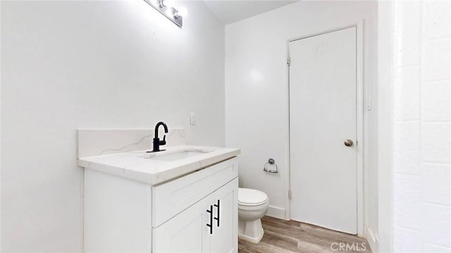 bathroom featuring toilet, wood finished floors, and vanity