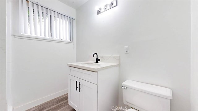 bathroom featuring toilet, baseboards, wood finished floors, and vanity