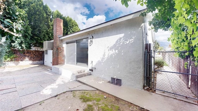 exterior space featuring a gate, a patio area, fence, and stucco siding