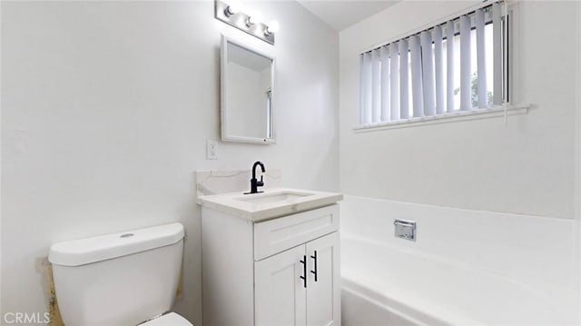 bathroom featuring a washtub, vanity, and toilet