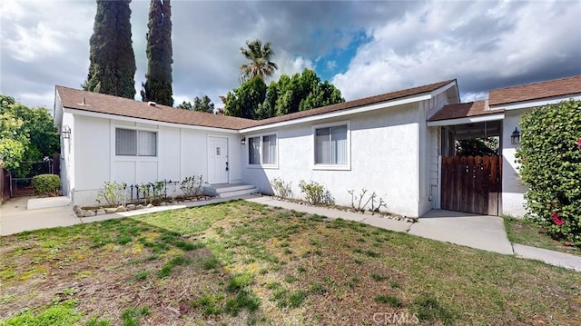 ranch-style house featuring a front yard, fence, and stucco siding